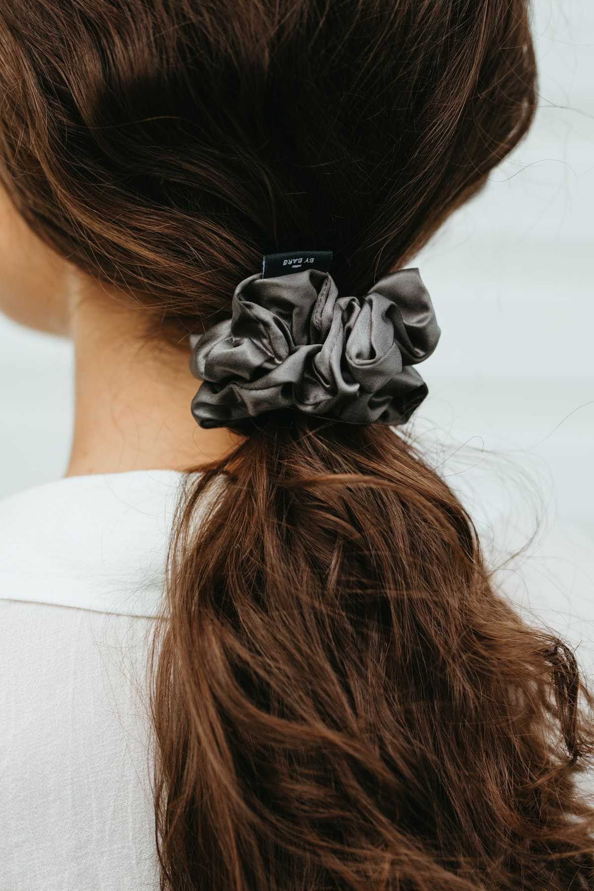Stor mörkgrå sidensnodd scrunchie i långt brunt hår