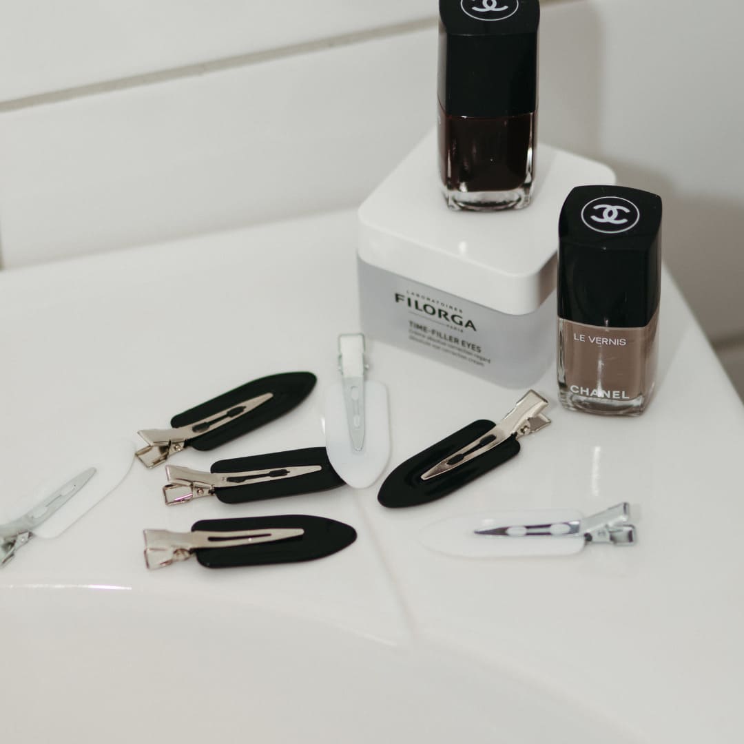 Stilleben med vita och svarta makeup clips och skönhetsprodukter