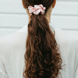 Stor rosa sidensnodd i scrunchie modell i långt brunt lockigt hår